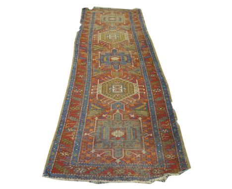 A Kazak style runner
Of typical rectangular elongated form on a predominantly red ground with blue banding and geometric form