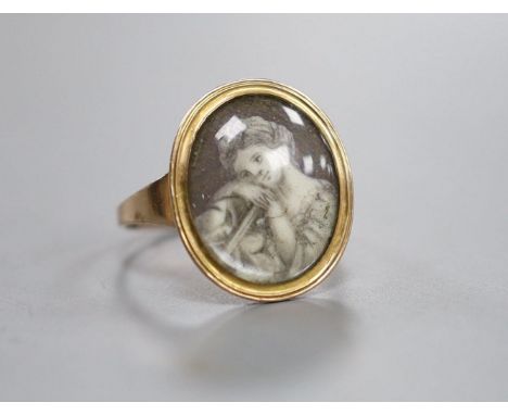 An early 19th century yellow metal ring inset with ivory? panel of a young lady,below a glazed panel and engraved monogram to