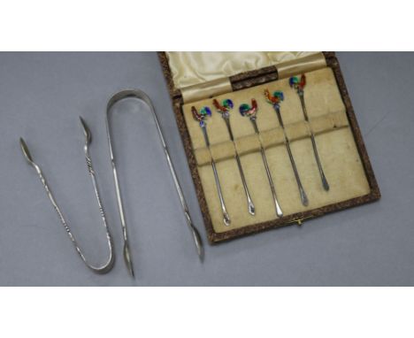 Five silver and enamel cocktail sticks and two pairs of silver sugar tongs.