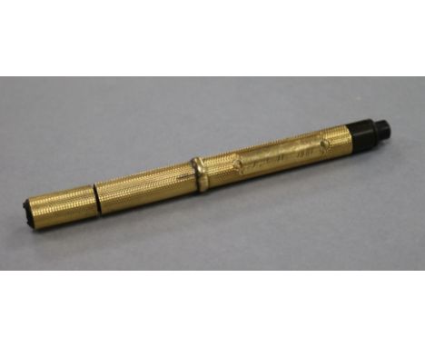 An Edwardian engine turned yellow metal fountain pen, with engraved inscription, 12.6cm.