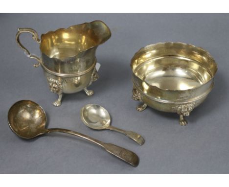 A George V silver cream jug and sugar bowl and a 19th century silver caddy spoon and sauce ladle.