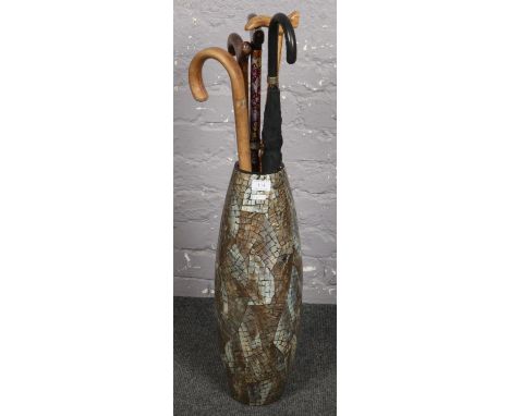 A large ceramic vase with a collection of wooden/metal walking sticks/umbrella  