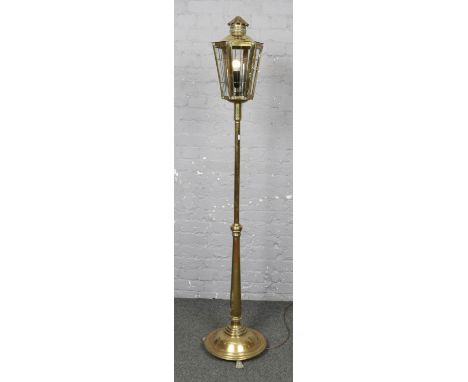 A brass floor standing lantern, converted to electric, with lion paw feet. (Height 186cm).  