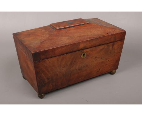 A mahogany tea caddy raised on small brass ball feet.  