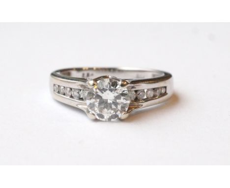 DIAMOND SOLITAIRE RING
the round brilliant cut diamond approximately 1ct, flanked by channel set diamonds to the shoulders to