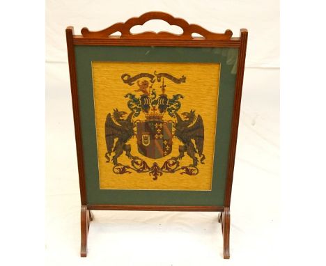 EDWARDIAN MAHOGANY FRAMED FIRESCREEN
with needlework 'Crest' panel behind glass, raised on shaped supports, 103cm high x 65cm