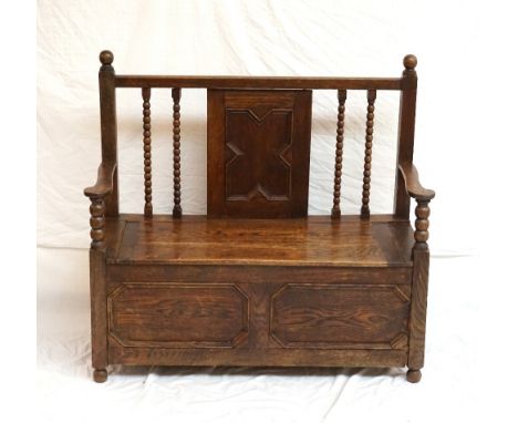 1920's OAK HALL BENCH
with a central panelled back flanked by bobbin turned supports, the shaped arms above a lift up seat wi