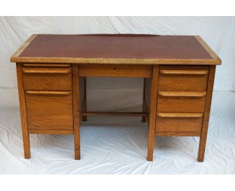 1950's OAK DESK
with an inset leatherette top above an arrangement of seven drawers, 137.5cm wide