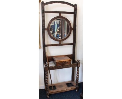 Antique oak heavily carved mirror backed hall stand, the top with coat hooks above stick stand base with two drip trays, 200c