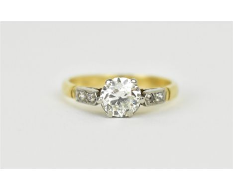 A yellow metal, white metal and diamond solitaire ring, roughly 0.78 carat, flanked with two diamond accents either side, cla