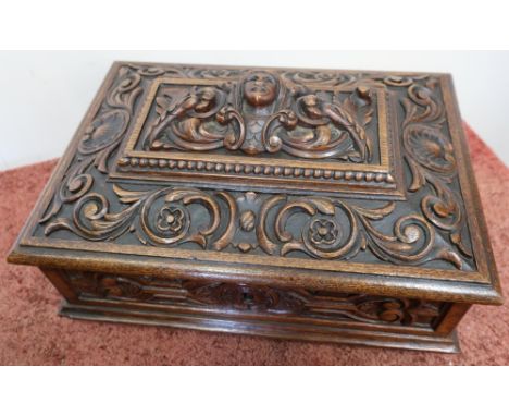 Elaborately carved rectangular oak table box with hinged lift up lid and light oak fitted interior, on four raised turned sup