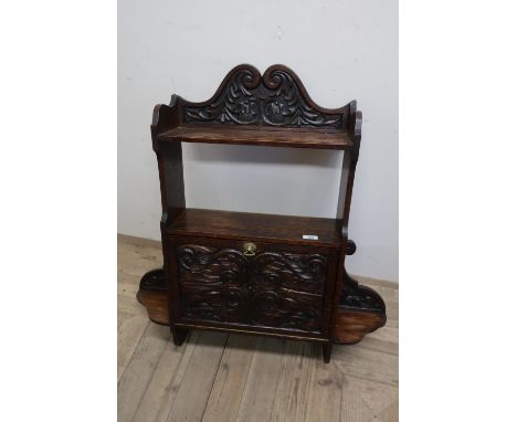 Carved oak wall shelf with raised swan neck pediments above shelf and open centre, above heavily carved fall front revealing 