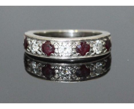 An 18ct white gold ring, the top set with alternating stones, three diamonds and four ruby coloured stones, estimated total d