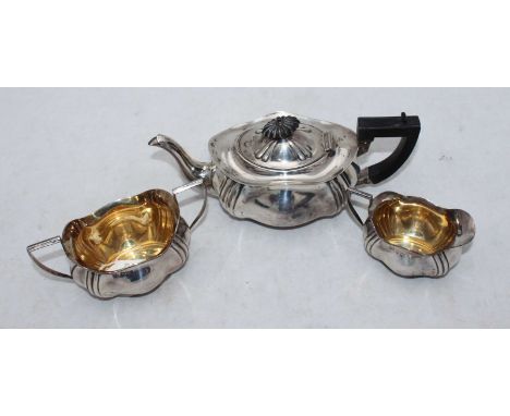 An Edwardian three-piece silver tea set comprising teapot, cream and sugar bowl, of serpentine shape with vertical reeded cor