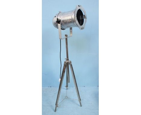 An industrial style, chrome studio/stage light raised on extendable tripod base.