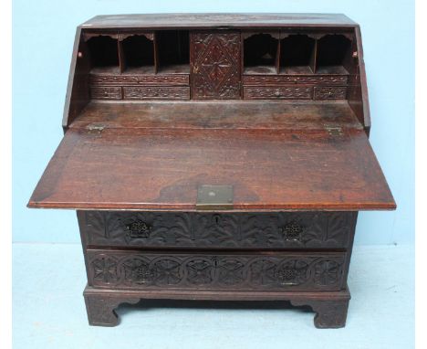 A 19th century carved and dark fumed oak bureau, with sloped front carved with cherubs riding lions and scrolling foliage, en