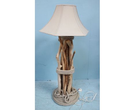 A floor standing lamp, with cream shade, raised on a support constructed from multiple sticks and bound by ropes. 115cm high.