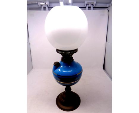 An antique brass oil lamp with blue glass reservoir, chimney and opaque glass shade, height 56 cm  