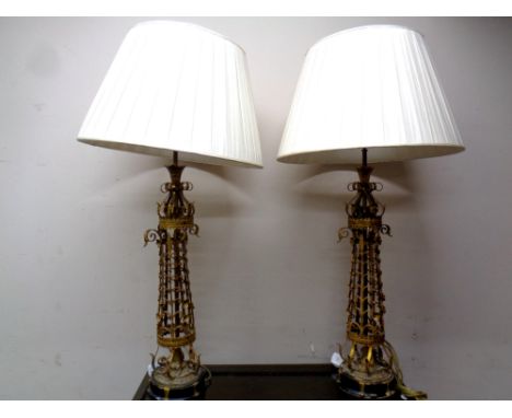 A pair of ornate gilt metal table lamps with shades, lamp bases 90 cm 