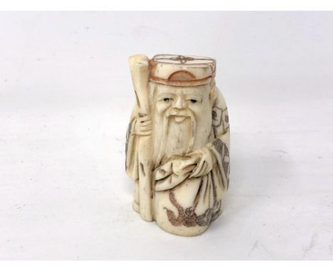 A Japanese carved bone netsuke - Village elder carrying a long staff. 