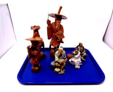 A tray containing oriental bisque porcelain figures, carved wooden figures, carved elephant candlestick 