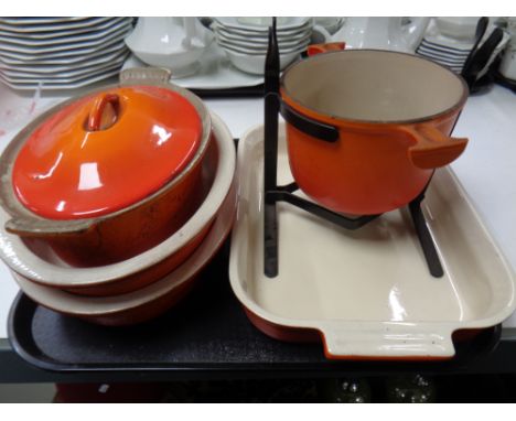 Four ceramic Le Creuset oven dishes, one with cast iron lid, together with a Le Creuset cast iron fondue pot on stand  
