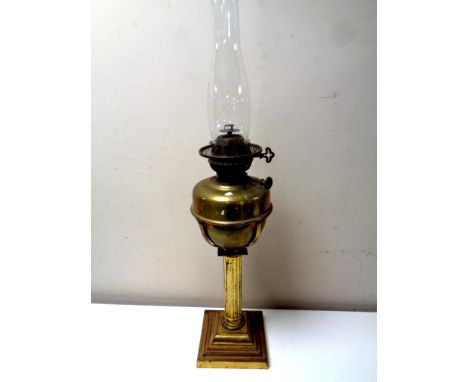An antique brass Corinthian column oil lamp with glass chimney, height 69.5 cm  