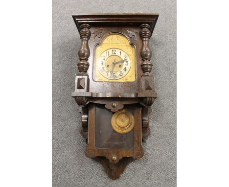 An antique oak cased wall clock with brass dial, pendulum and key 