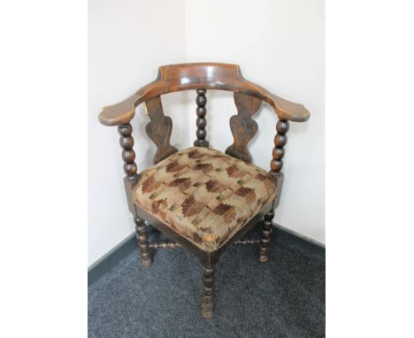 An early 20th century oak corner chair on bobbin legs 