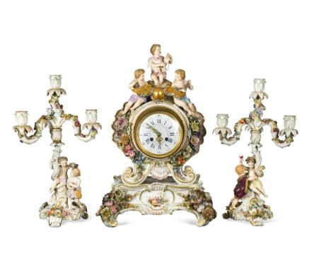 A Meissen porcelain clock garniture, late 19th century,  the cartouche shaped clock mounted with cherubs and encrusted with f