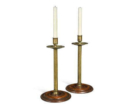 A pair of George III mahogany and brass candlesticks,  of unusual form, each with a brass drip tray above a seemed brass stem