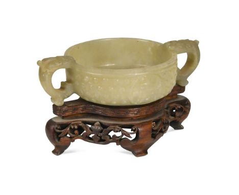 A Chinese jade tab-handled bowl in an archaic style, Qing Dynasty, 19th century, with fo-dog scroll handles, the circular bow
