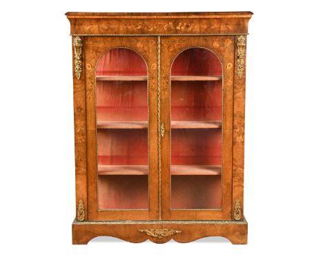 An inlaid walnut and gilt metal display cabinet, 19th century, the moulded rectangular top over two arched glazed doors enclo