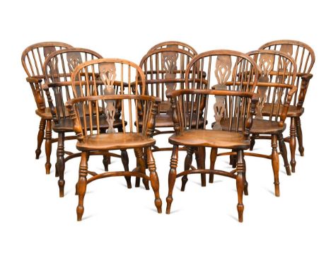Eight yew and elm stick back armchairs, early 19th century, with solid saddle shaped seats on turned supports united by crino