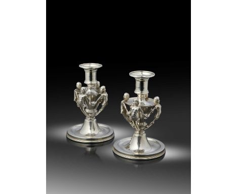 By Omar Ramsden, a pair of Arts and Crafts 'Child Nymphs' silver candlesticks,  London 1936, circular form, spot-hammered dec