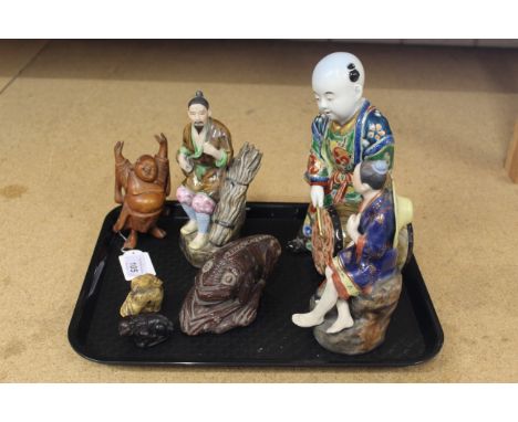 A carved bone netsuke, a wooden carved Buddha, three porcelain figurines of oriental men plus a carved stone frog type creatu