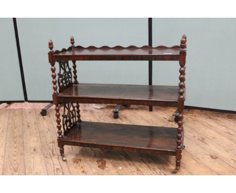 An early Victorian rosewood three tier whatnot on bobbin turned supports and fretted ends