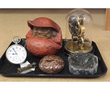A German made small brass clock under a plastic dome, a Dobson &amp; Sons Piccadilly glass ball clock, carved stones and wood
