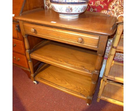 An Ercol style elm three tier drinks trolley fitted single drawer and raised on castors