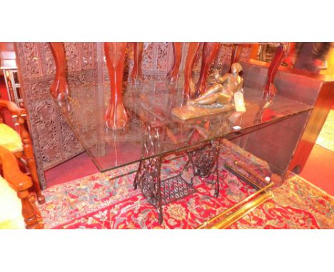 A plate glass dining table with vintage cast iron sewing machine base