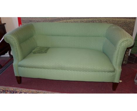 A late 19th century two seater sofa upholstered in green patterned fabric raised on tapering supports 