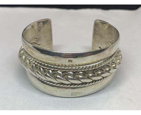 A LARGE HEAVY SILVER BANGLE WITH ROPE DESIGN 