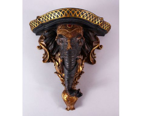 A NICELY CARVED INDIAN ELEPHANT FORMED WALL BRACKET, carved with an elephant head amongst gilded scroll, 32cm x 33cm