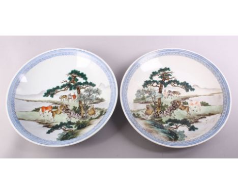 A GOOD PAIR OF CHINESE REPUBLIC FAMILLE ROSE PORCELAIN PLATES, each decorated with figures upon horseback in landscapes, with