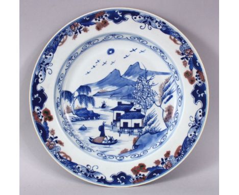 A CHINESE BLUE, WHITE &amp; IRON RED PORCELAIN PLATE, decorated with native waterside landscape views and mountains, with but