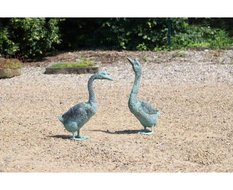 A pair of patinated bronze garden statues  modelled as two geese, with green colouring, 19cm wide 45cm deep tallest 77cm high