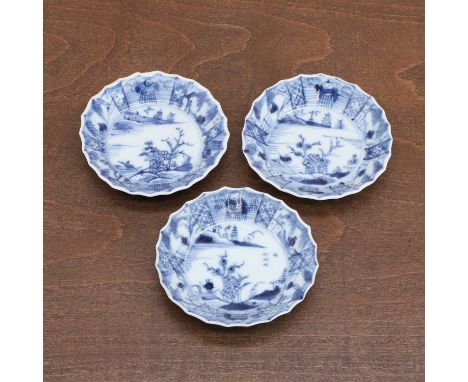 A group of three Chinese blue and white saucers, Kangxi (1662-1722), each with rounded sides rising from a circular foot to a