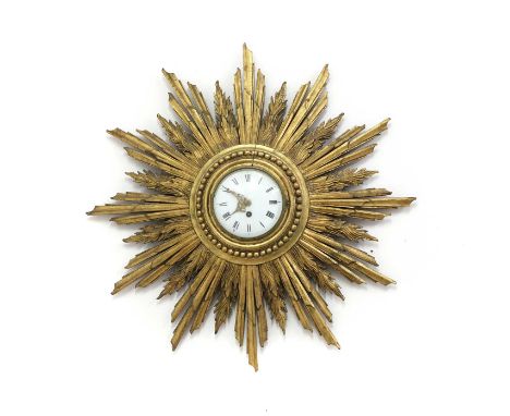 A French carved gilt wood Sunburst timepiece c.1900, with 14cm enamel dial, roman numerals, carved with radiating spars 66cm 