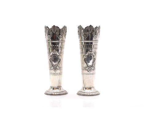 A pair of silver vases by William Hutton &amp; Sons, London 1902, with a shell and scrolled border, to vacant cartouches, on 