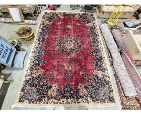 North East Persian signed red ground Meshed carpet with large centralised floral medallion enclosed by stylised floral shapes